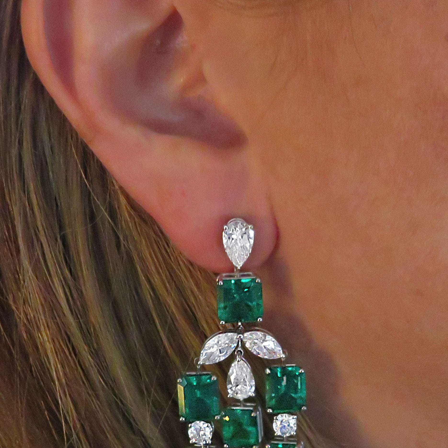 Elegant display of VIVID 24Ct Colombian Emerald & Diamond Dangle Earrings in Platinum worn, highlighting the vibrant Imperial Green emeralds and dazzling diamonds, perfect for luxury occasions.