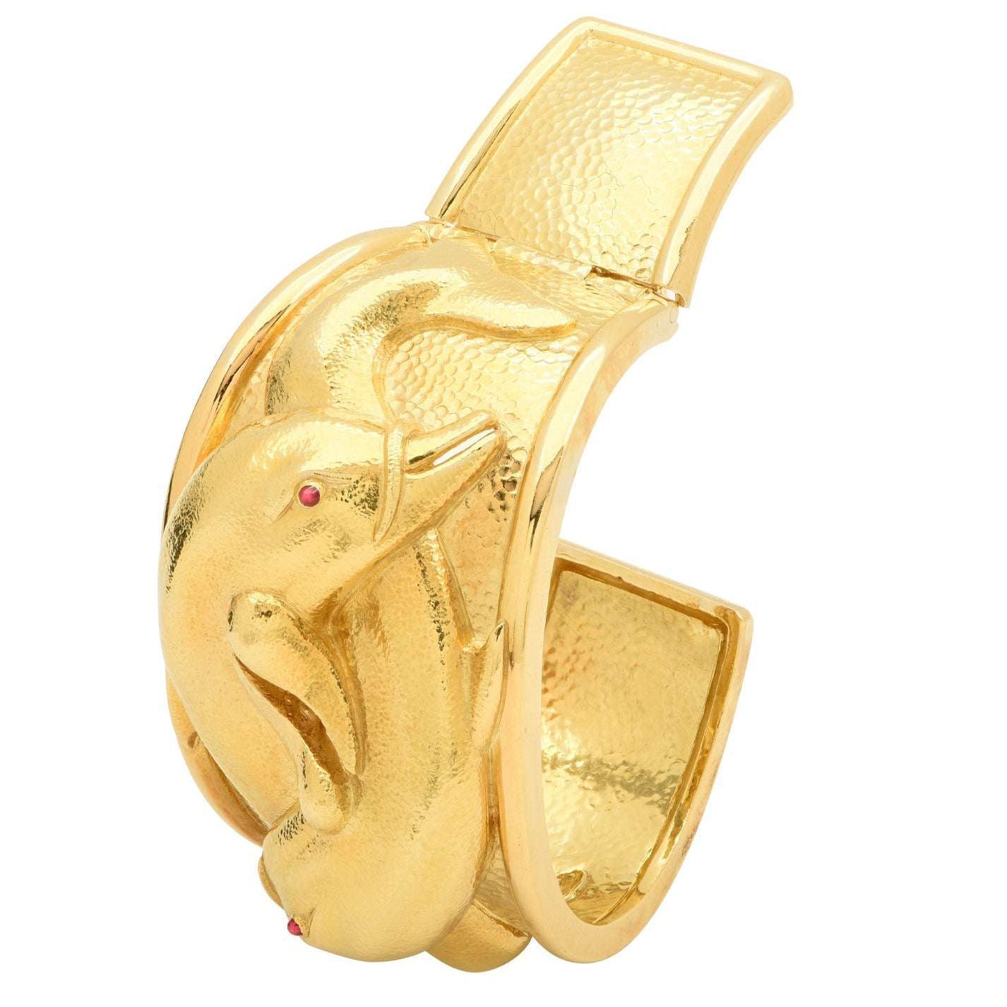 David Webb 18K Yellow Gold Dolphin Cuff Bangle with Ruby Accents, an exquisite designer jewelry piece by Vivid Diamonds, featuring intricately designed dolphins and vibrant ruby eyes, perfect for adding luxury to any collection.