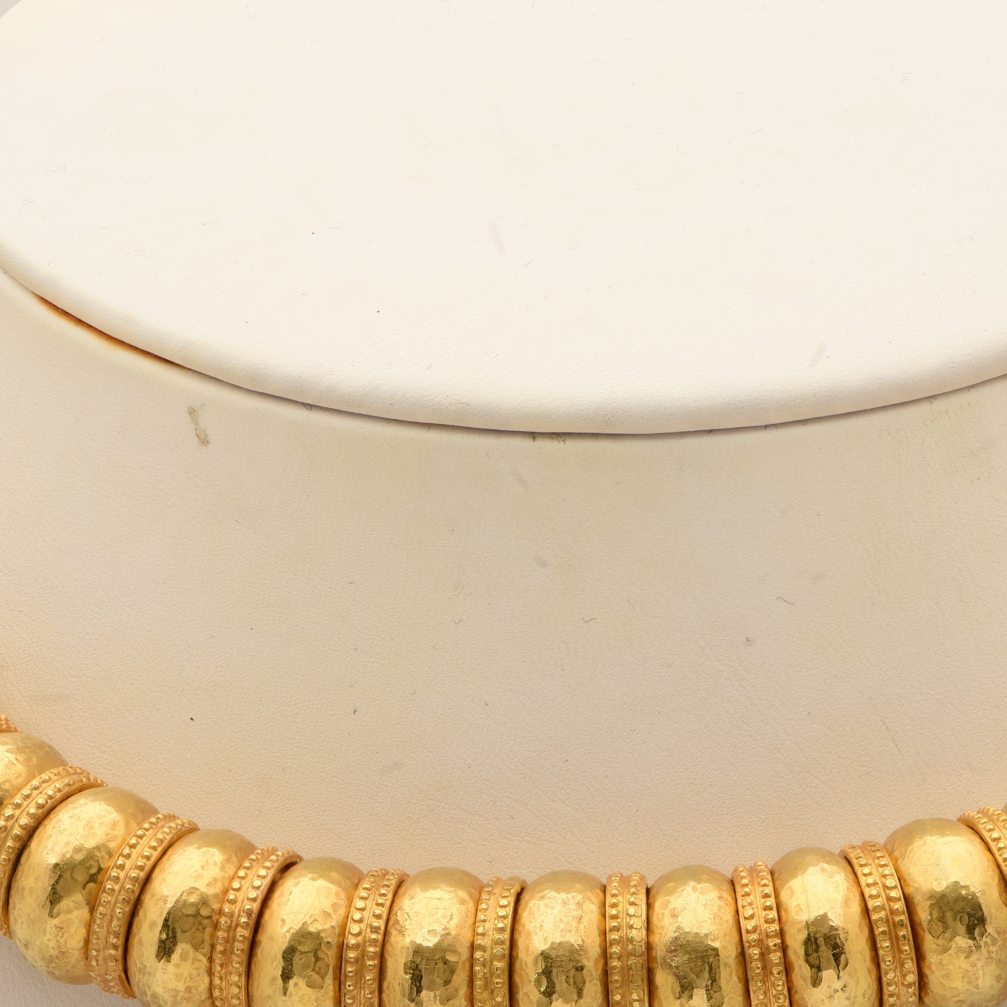 Ilias Lalaounis 18K Yellow Gold Bead Necklace resting on a display, exemplifying the artisanal quality and timeless elegance of luxury jewelry from Vivid Diamonds.