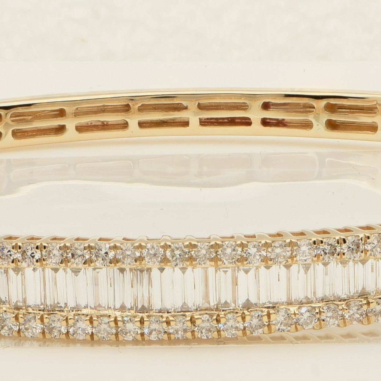 Elegant 14K Yellow Gold Diamond Bangle Bracelet by Vivid Diamonds, showcasing a breathtaking arrangement of round brilliant and baguette diamonds in a sophisticated triple-row design, embodying luxury and brilliance.