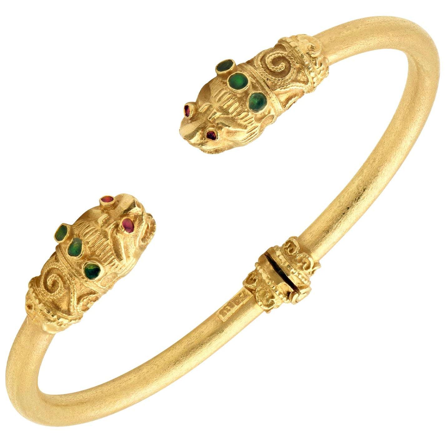 18K Yellow Gold Double Lion Cuff Bracelet with Ruby Eyes & Emerald Accents by Vivid Diamonds, featuring intricately sculpted lion heads adorned with vivid gemstones.