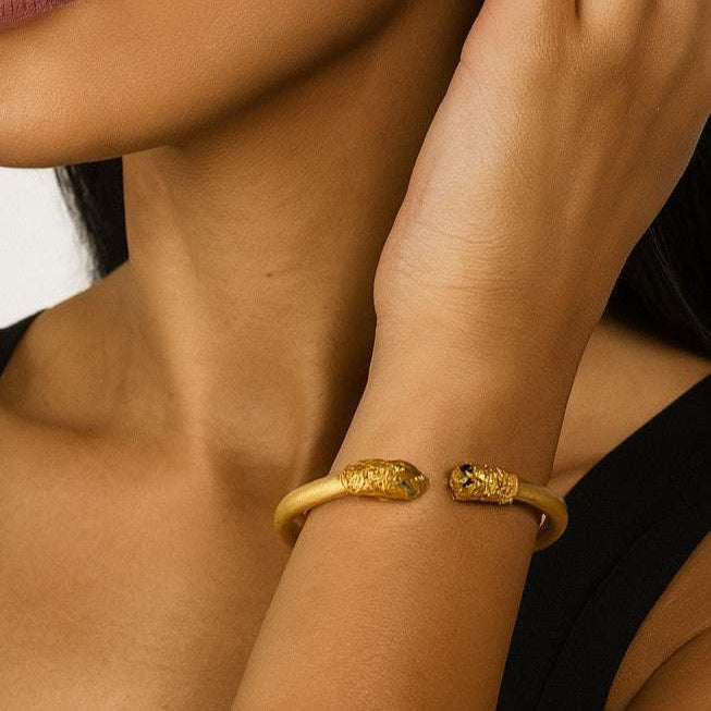 Model wearing the 18K Yellow Gold Double Lion Cuff Bracelet with Ruby Eyes & Emerald Accents by Vivid Diamonds, showcasing its luxurious design and elegant style.