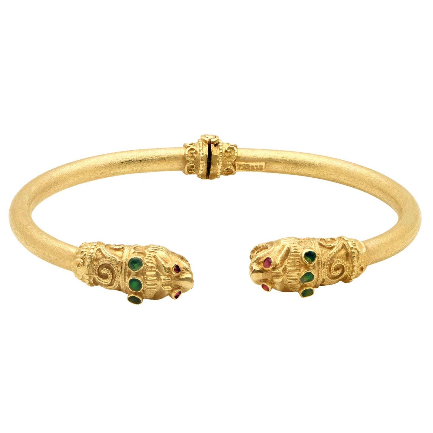 Close-up view of the 18K Yellow Gold Double Lion Cuff Bracelet with Ruby Eyes & Emerald Accents by Vivid Diamonds, highlighting the intricate details and colorful gemstones.