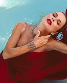 Luxury model wearing the Diamond & Ruby Cuff Bangle Bracelet by Vivid Diamonds while elegantly posing in a pool, showcasing the bracelet's intricate design and vibrant colors.