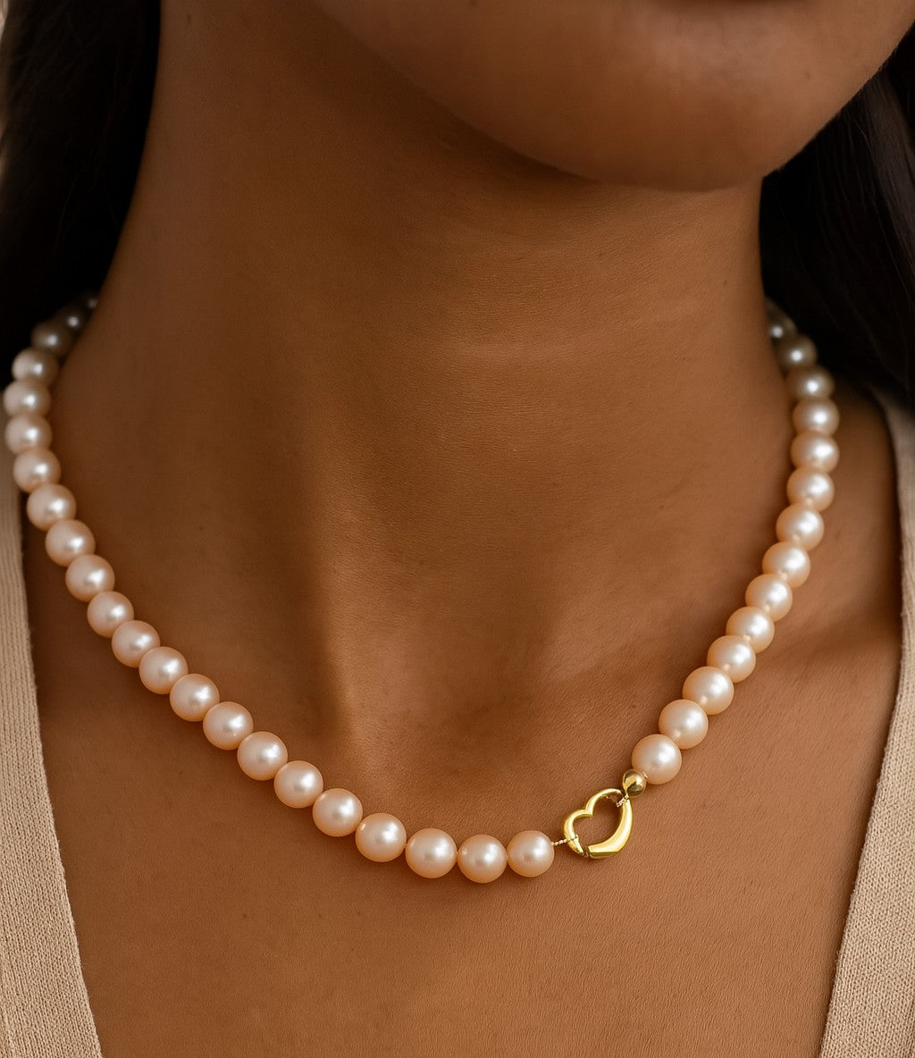 Close-up of an Elegant Pearl Necklace worn, highlighting its exquisite pearls and 18K yellow gold heart clasp, perfect for every occasion by Vivid Diamonds.